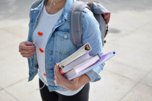 University student with backpack and books in hand.